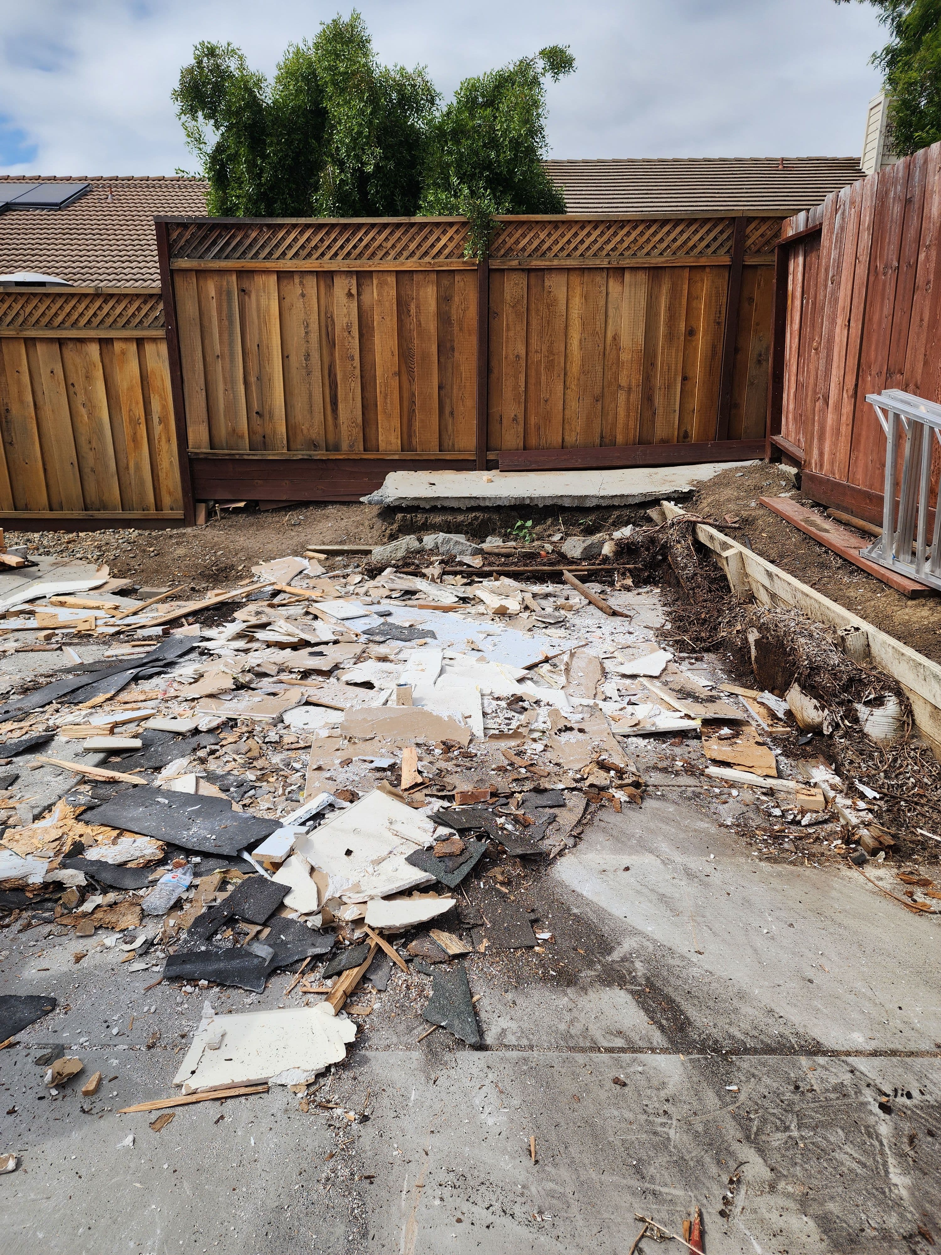 Construction site with debris and damaged pavement, highlighting yard renovation.